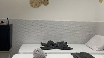 A hotel room with a bed, a flat-screen TV, and a wall-mounted air conditioner.