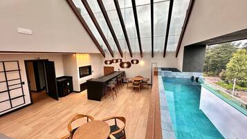 A modern interior with a pool, wooden furniture, and a view of the outdoors.
