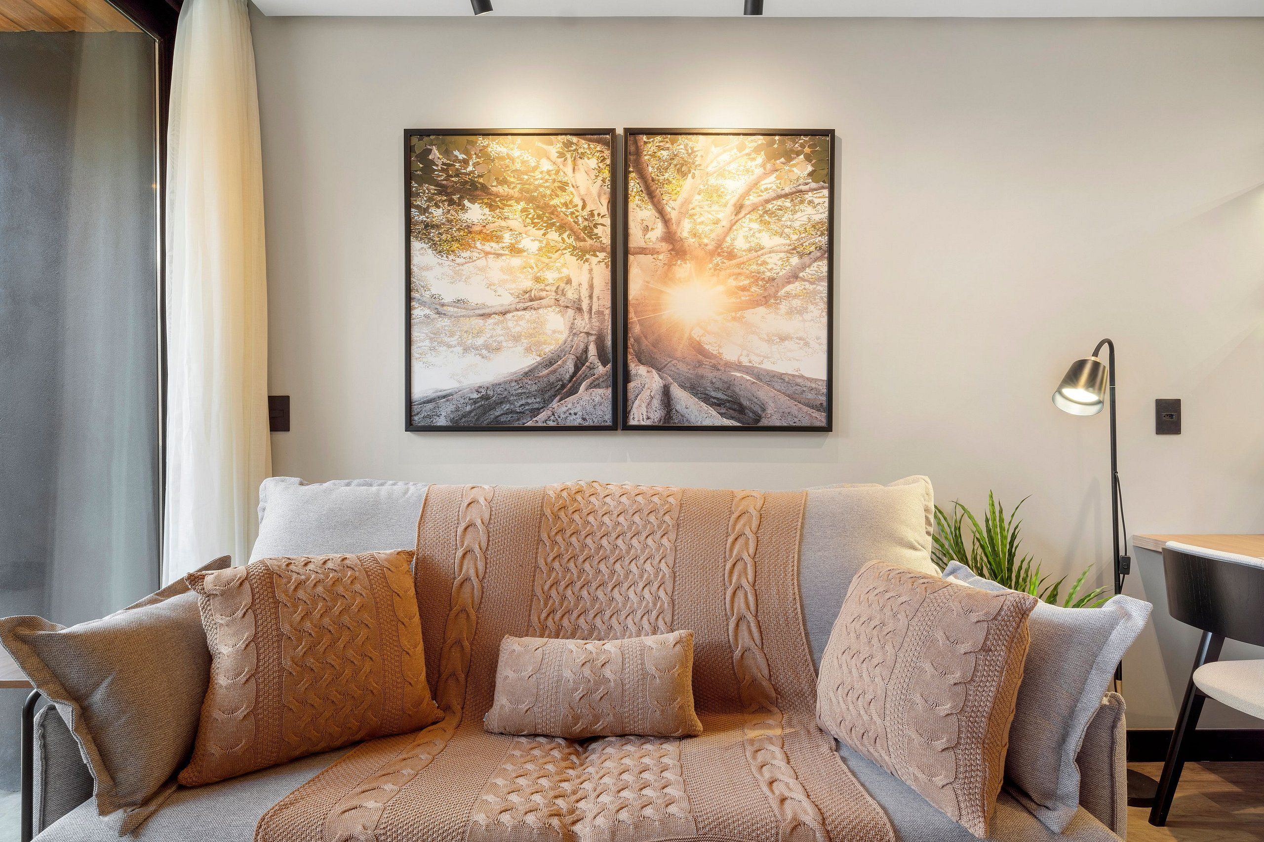 Una sala moderna con un conjunto de sofás, una lámpara de pie y un cuadro grande enmarcado en la pared.