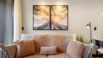 Una sala moderna con un conjunto de sofás, una lámpara de pie y un cuadro grande enmarcado en la pared.