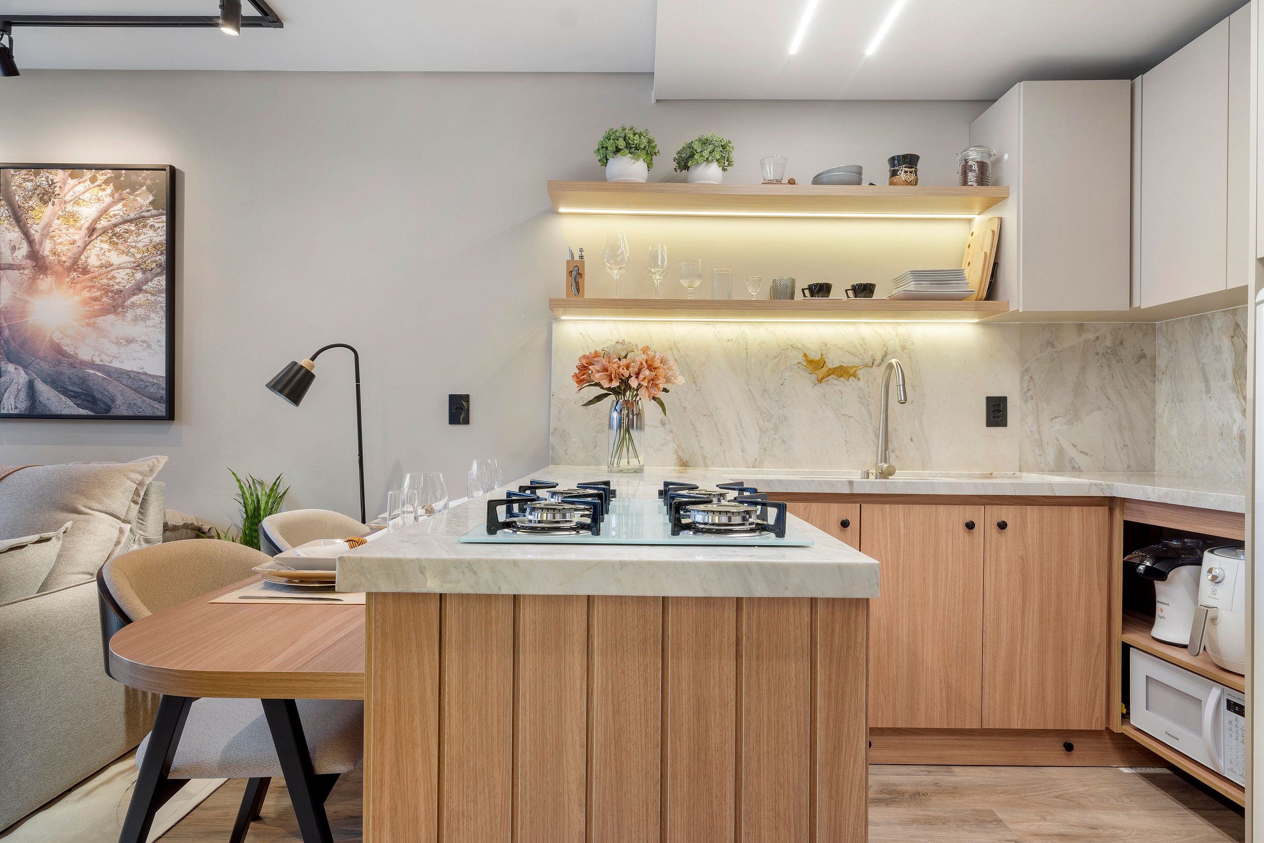 Een moderne keuken met een centraal eiland, inbouwapparatuur en een zithoek met een bank en tafel.