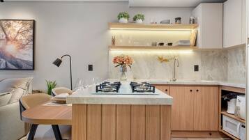 Een moderne keuken met een centraal eiland, inbouwapparatuur en een zithoek met een bank en tafel.