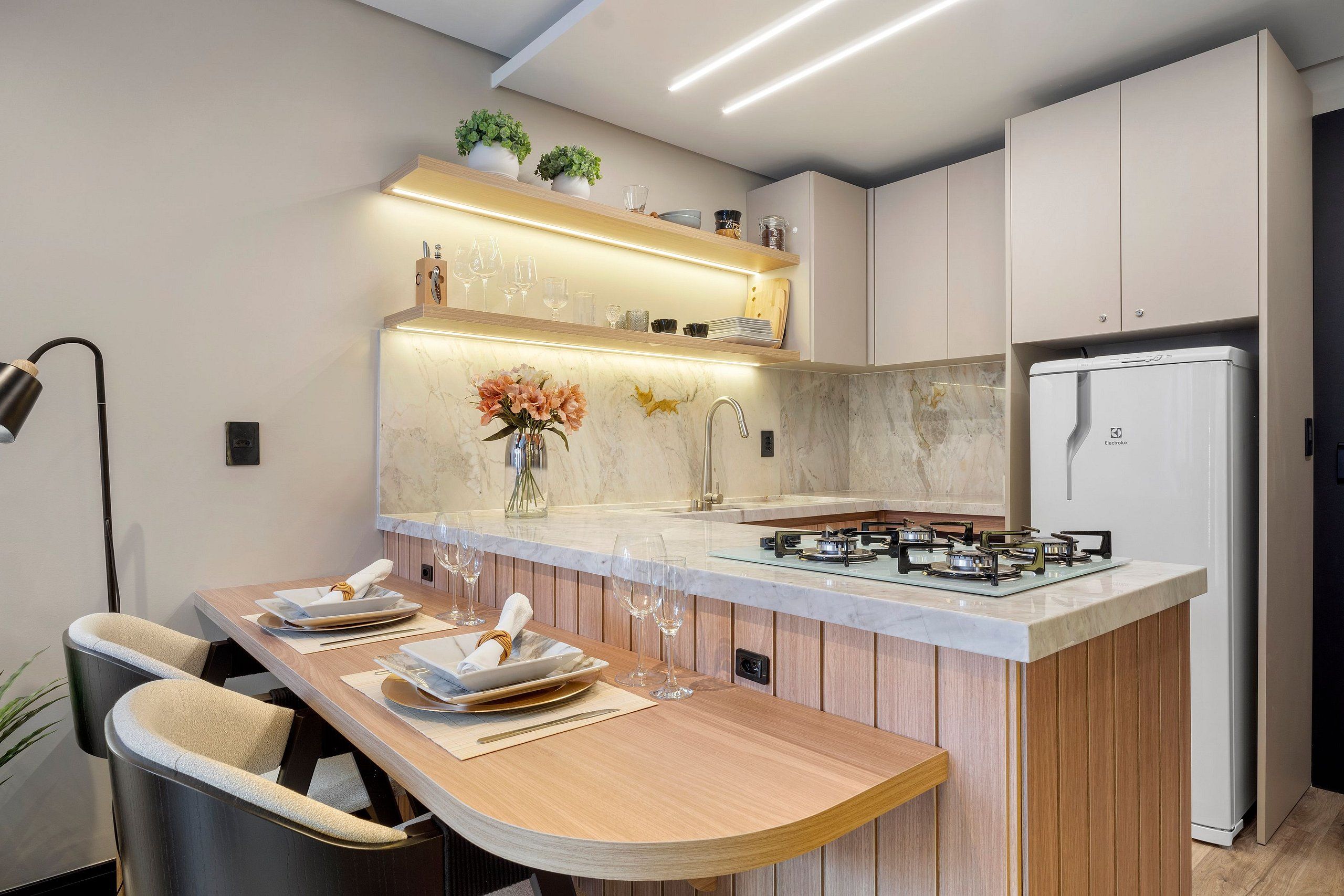Una cocina moderna con una isla central, electrodomésticos integrados y una zona de comedor con sillas.