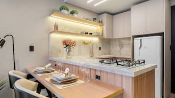 Una cocina moderna con una isla central, electrodomésticos integrados y una zona de comedor con sillas.