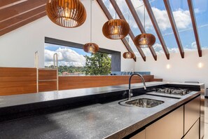 Una cocina moderna con una isla grande, pileta de acero inoxidable y detalles de madera.
