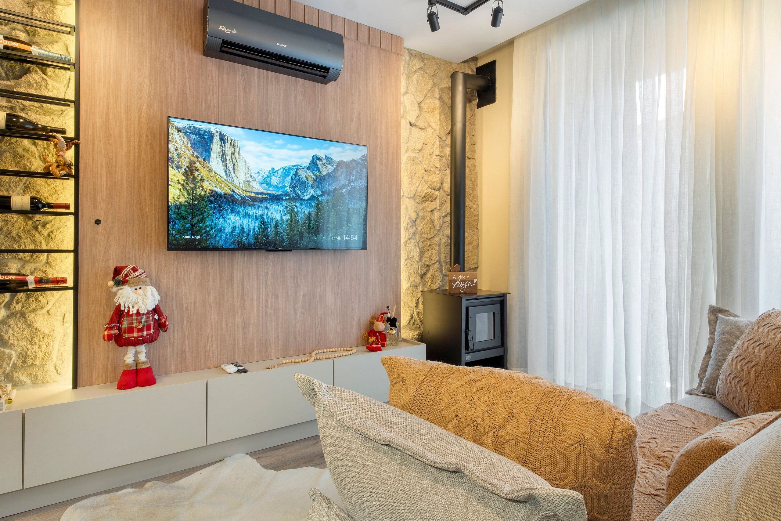 Una sala de estar moderna con un televisor de pantalla plana montado, una chimenea y un espacio para vinos.