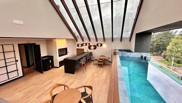A modern interior with a pool, wooden furniture, and a view of the outdoors. - Apto YOU 206 (Canela)