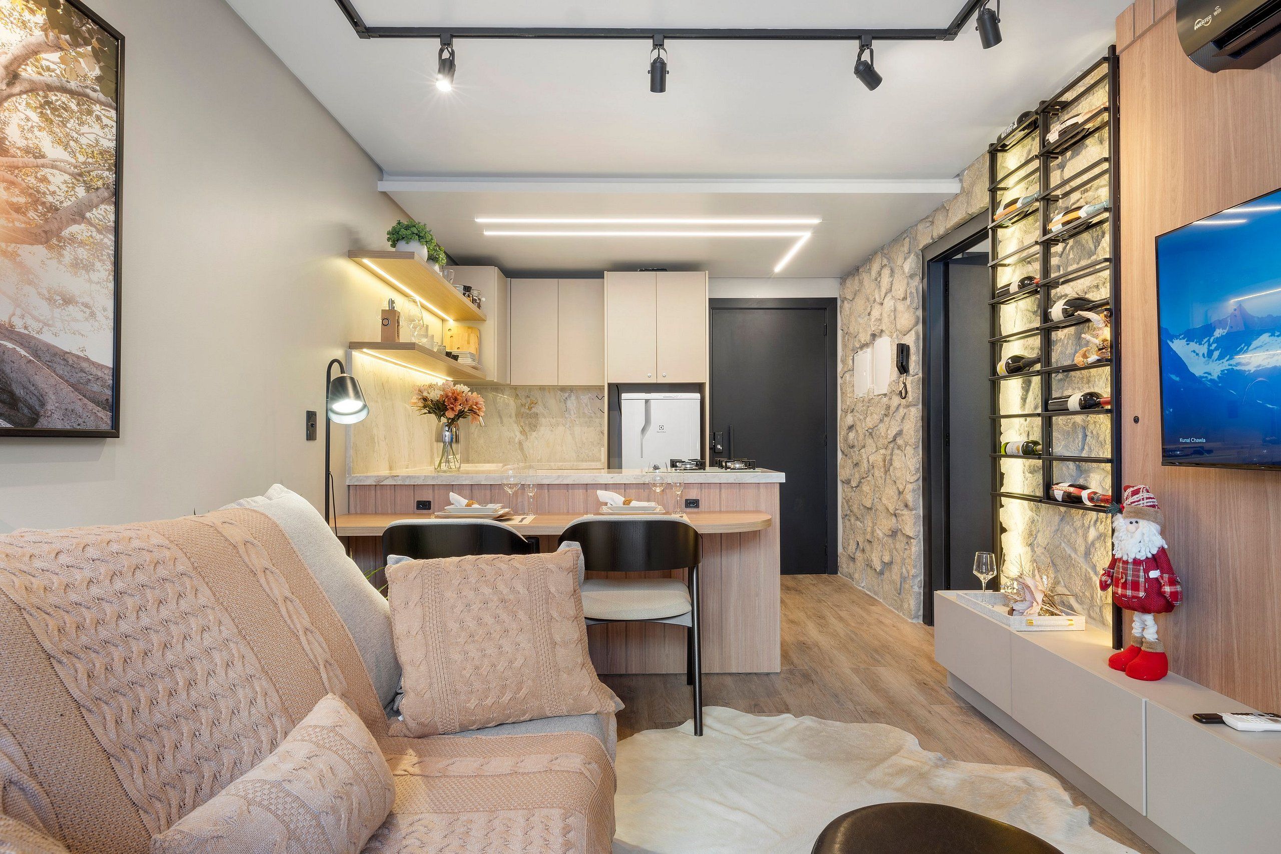 A modern kitchen with built-in appliances, a dining area with a sofa, and a wine rack with bottles.