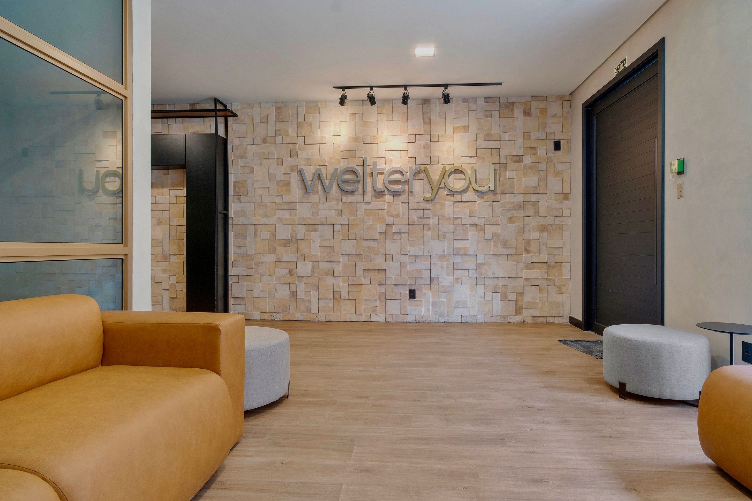Een receptiezone met een stenen muur, een 'welteryou' bord en twee banken.