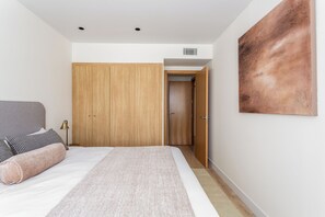 Ein Schlafzimmer mit Bett, Kleiderschrank, einer Tür und einem an der Wand hängenden Kunstwerk.