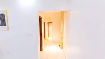Un pasillo con una puerta que da a otra habitación, un interruptor de luz y un cuadro en la pared.