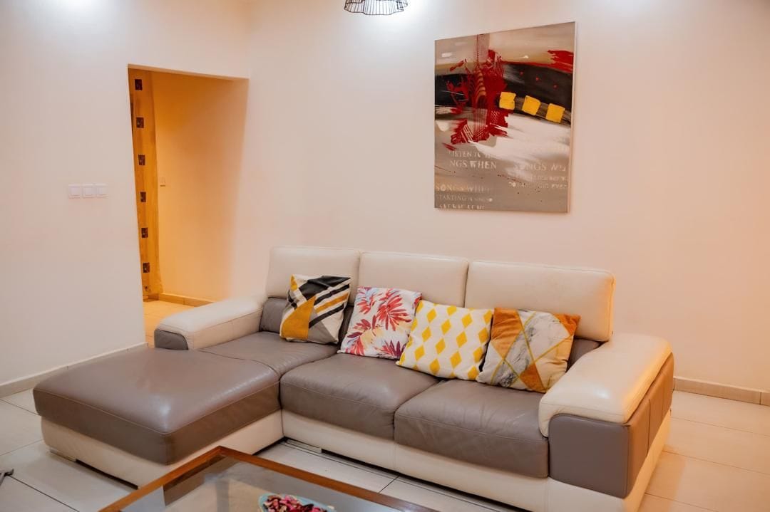 Un salon moderne avec un canapé d’angle, une table basse et une œuvre d’art encadrée accrochée au mur.
