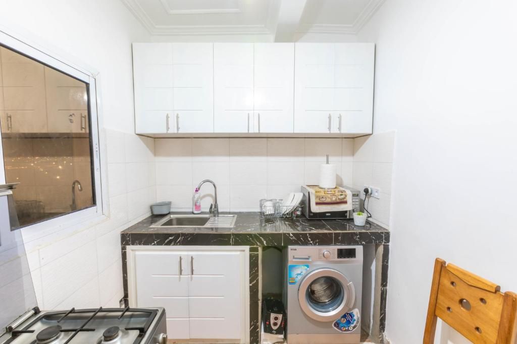 Cocina compacta con armarios blancos, un lavabo, una estufa y lavadora integrada.