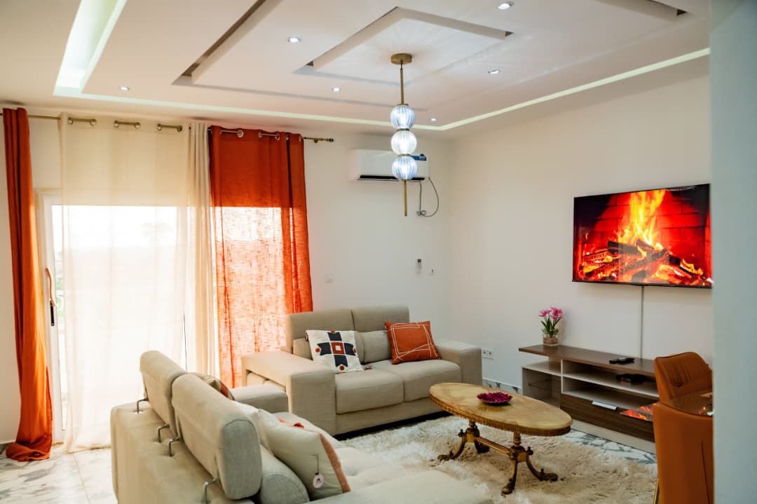 A modern living room with a sofa, a coffee table, and a flat-screen TV mounted on the wall.