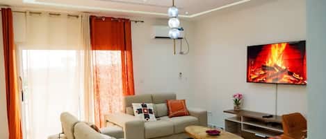 A modern living room with a sofa, a coffee table, and a flat-screen TV mounted on the wall.