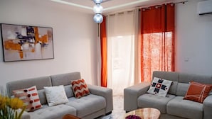 A modern living room with two sofas, a coffee table, and a painting on the wall. - EDEN GARDEN LUXURIOUS GUEST HOUSE (Yaoundé)