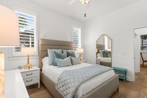 A bedroom with a bed, bedside tables, a mirror, and a window with blinds. - New to Rental Market! Located in Prestigious Carillon Beach! (Panama City Beach)