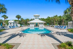 A pool area with a central pool, lounge chairs, and a building with a tower-like structure. - New to Rental Market! Located in Prestigious Carillon Beach! (Panama City Beach)