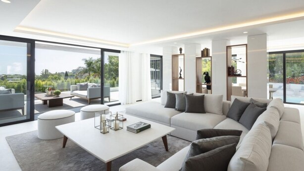 A modern living room with a large sofa, a coffee table, and a view of the outdoors. - Vrbo Property (Marbella)