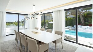 A modern dining room with a large table, chairs, and a chandelier. - Vrbo Property (Marbella)