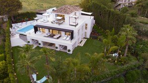 A modern two-story house with a rooftop pool, surrounded by lush greenery and palm trees. - Vrbo Property (Marbella)