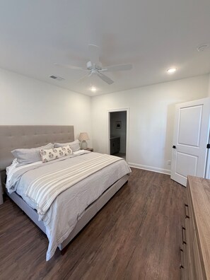Ein Schlafzimmer mit Bett, Deckenventilator und Tür.