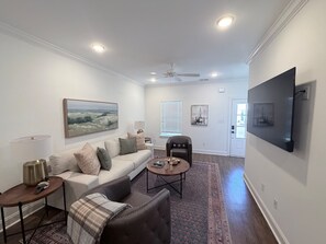Ein Wohnzimmer mit Sofa, Sessel, Couchtisch und Kunstwerken an den Wänden.