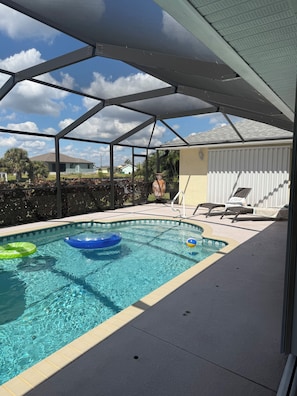 Ein Schwimmbecken mit Luftmatratzen, eine überdachte Terrasse und ein Haus im Hintergrund.