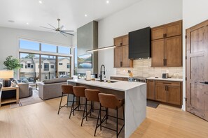 A modern kitchen with a large island, bar stools, wooden cabinets, and a view of the outside. - Brand-New Frisco Townhome | Modern Mountain Retreat Near Ski Resorts (Frisco)