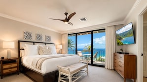 A hotel room with a large bed, a ceiling fan, a TV, a balcony with a view of the ocean, and a desk with a lamp. - Kapalua Bay Villas | 2 Oceanfront Villas, Sleeps 12 | Car Incl. w/ 6+ Nights | ML-4691 by KBM (Lahaina)