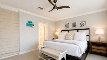A bedroom with a bed, bedside tables, a bench, a ceiling fan, and artwork on the walls.