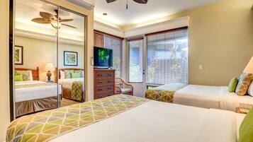 A hotel room with two beds, a television, a ceiling fan, and a window with blinds.