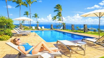 A poolside area with lounge chairs, umbrellas, and a view of the ocean.
