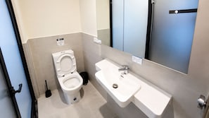 Et badeværelse med toilet, håndvask og spejl.