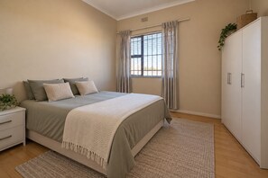 Ein Schlafzimmer mit einem Bett, einem Nachttisch, einem Kleiderschrank und einem Fenster mit Vorhängen.