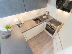 Eine kleine Küche mit eingebautem Backofen, einem Kochfeld und einem Spülbecken.