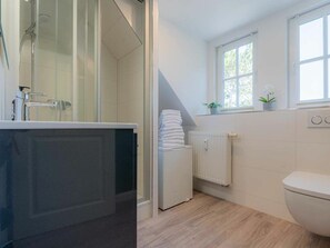 Ein Badezimmer mit Dusche, Toilette und Fenster.