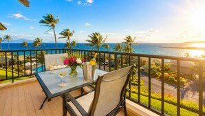 A balcony with a table, chairs, a bottle of champagne, and a vase of flowers. - Kapalua Bay Villas | 3 Oceanfront Villas, Sleeps 16 | Car Incl. w/ 6+ Nights | ML-4694 by KBM (Lahaina)