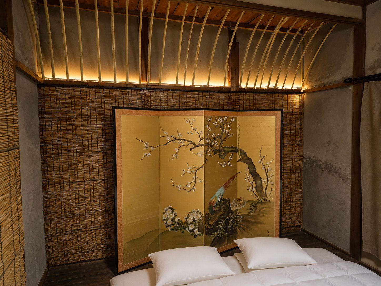 A traditional room with a tatami mat floor, a shoji screen with cherry blossoms, and a bed with white bedding.