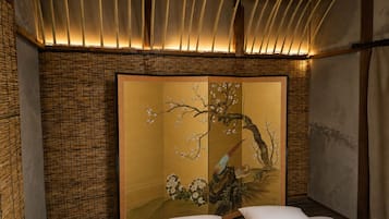 A traditional room with a tatami mat floor, a shoji screen with cherry blossoms, and a bed with white bedding.