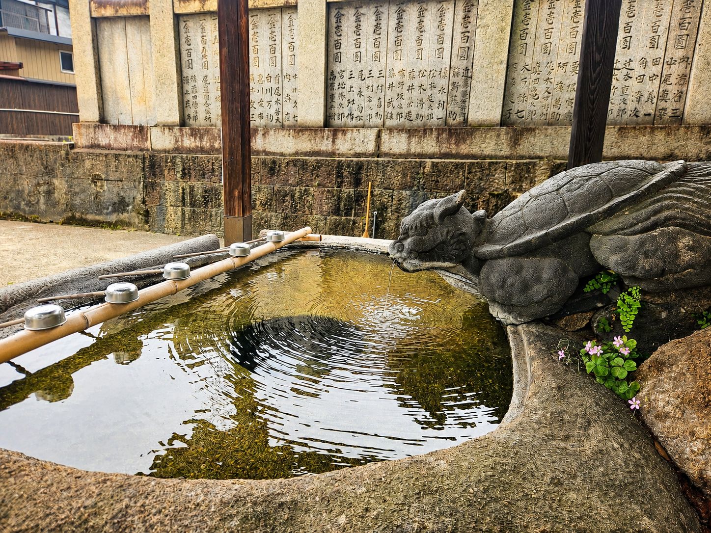 A stone fountain with inscriptions, a dragon sculpture, and a small pond.