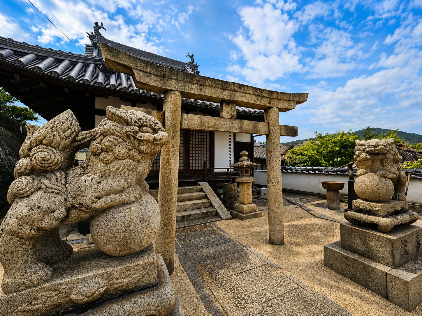 A traditional Japanese building with a tiled roof, stone lion statues, and a stone lantern.