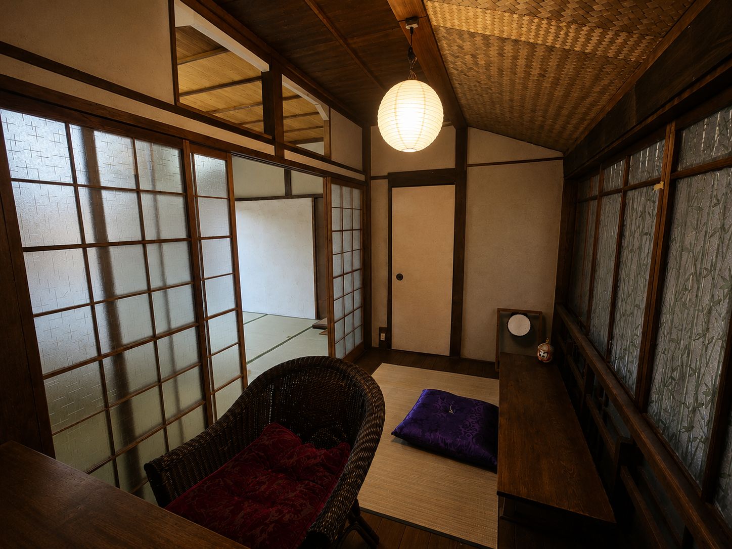 Een traditionele Japanse kamer met tatami vloeren, een lage houten tafel, een geweven stoel en een shoji schuifdeur.