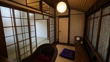 Een traditionele Japanse kamer met tatami vloeren, een lage houten tafel, een geweven stoel en een shoji schuifdeur.