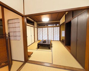 A traditional Japanese room with tatami flooring, sliding doors, and a low table with chairs.