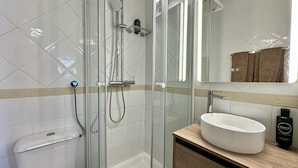 A modern bathroom with a glass-enclosed shower, a white sink, and a mirror above the sink. - Fort | Near the Beach | Sleeps 6 | Albufeira (Albufeira)