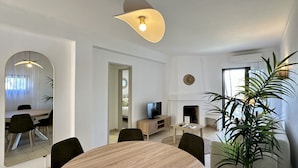 A modern living room with a dining area, a television, and a fireplace. - Fort | Near the Beach | Sleeps 6 | Albufeira (Albufeira)
