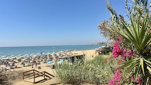 A beach with sun loungers and umbrellas, a wooden deck, and a view of the sea. - Fort | Near the Beach | Sleeps 6 | Albufeira (Albufeira)