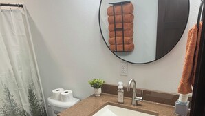 Ein Badezimmer mit Toilette, Waschbecken, Spiegel und Handtuchhalter.