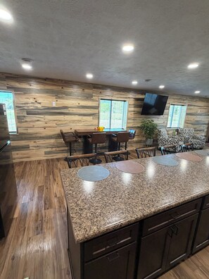 A modern kitchen with granite countertops, wooden flooring, and a dining area with a large table and chairs.